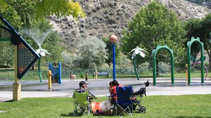 Un parco con un'area giochi, zone relax e uno sfondo collinare.