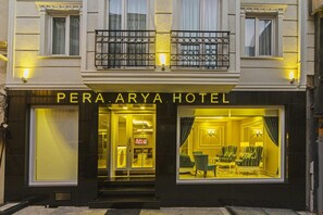 Exterior del Hotel Peraya, con una entrada destacada y un balcón sobre las puertas.