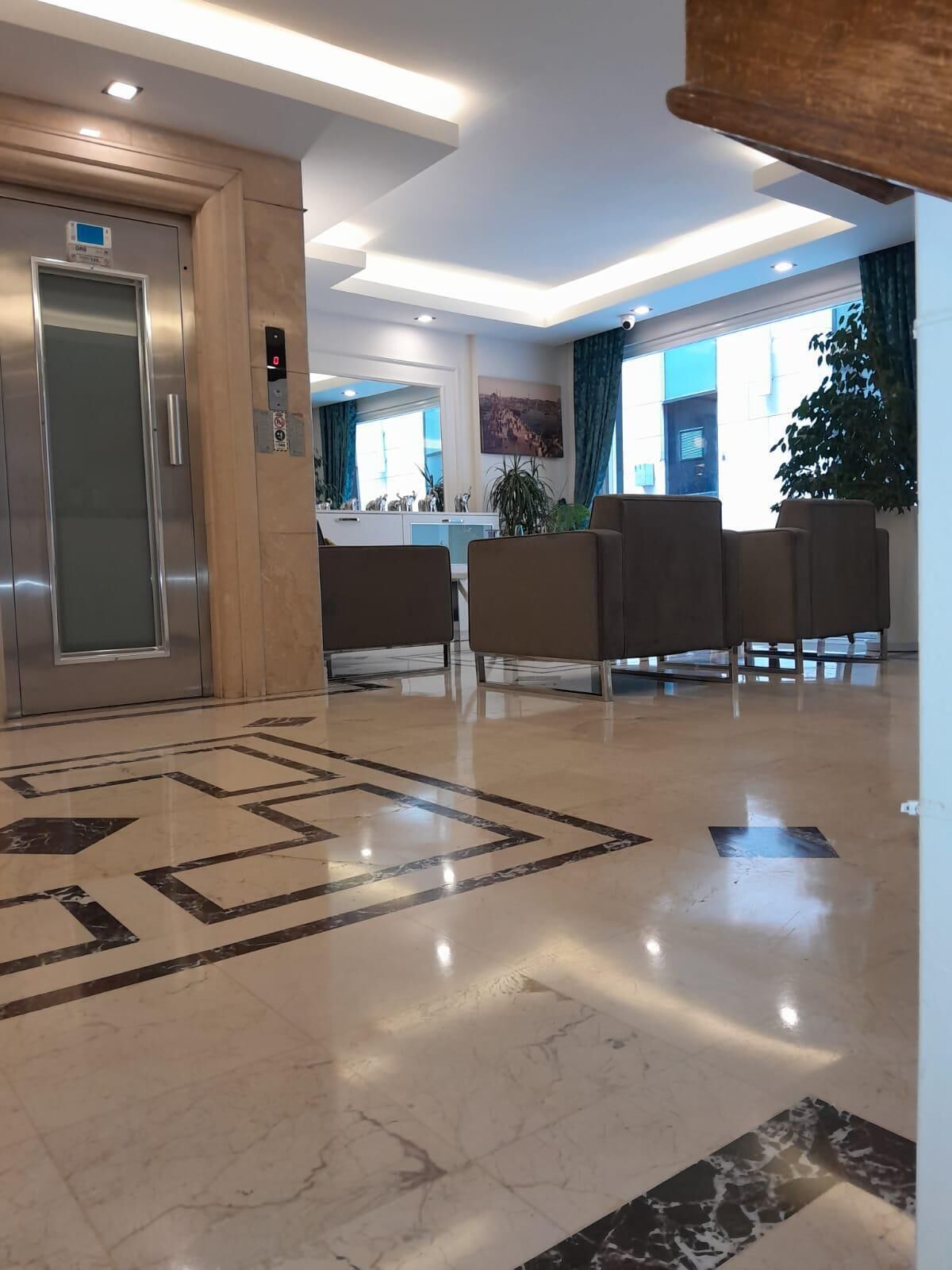 A modern lobby with a marble floor, a reception desk, and a seating area with chairs.
