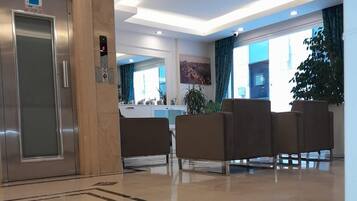 A modern lobby with a marble floor, a reception desk, and a seating area with chairs.