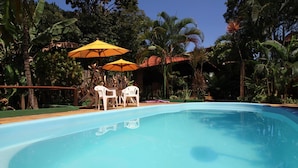 Una piscina amb cadires blanques i paraigudes grogues, envoltada de vegetació tropical exuberant.