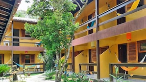 Un pati interior amb un arbre al centre, envoltat de plantes en testos i una cadira lliure.