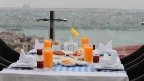 A table set with breakfast items and orange juice, overlooking a cityscape and river. - Troya Hotel (Istanbul)