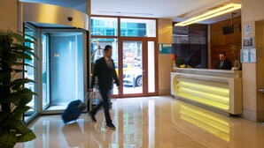 A hotel lobby with a reception desk, a glass door entrance, and a potted plant. - Troya Hotel (Istanbul)