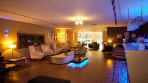 A modern hotel lobby with a seating area, a bar, and a view of the kitchen. - Troya Hotel (Istanbul)