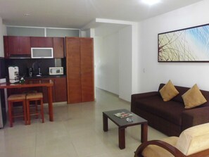 Un espacio habitable compacto con kitchenette, un sofá y una mesita de centro.