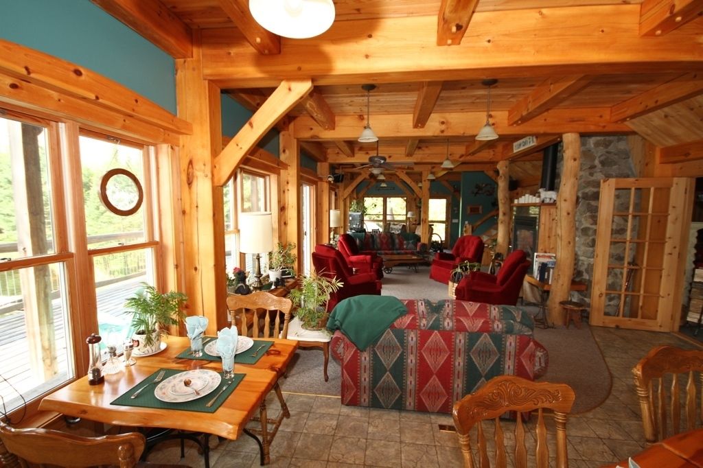 Un intérieur spacieux en bois, comprenant un coin repas, un canapé et une cheminée.