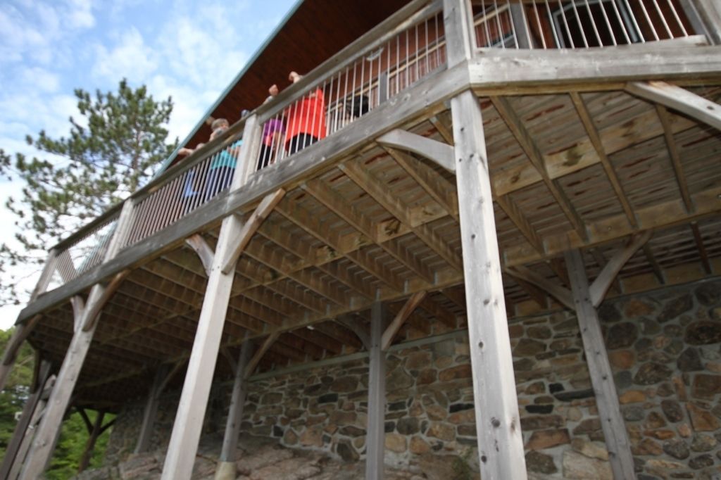 A wooden balcony with stone walls and a metal railing.