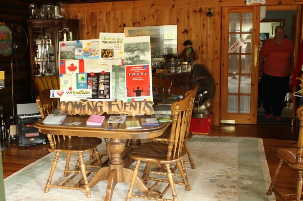 A wooden interior with a round dining table surrounded by chairs, a bulletin board with event flyers, and a door labeled "PRIVATE."
