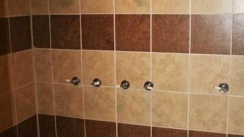 Área de duche com vários chuveiros e soalho em azulejo.