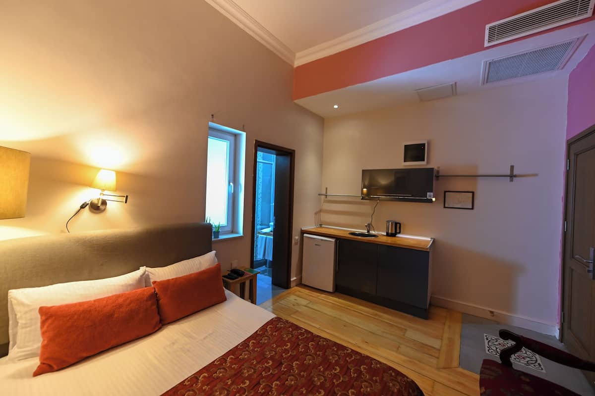 A hotel room with a bed, a desk, a television, and a door.