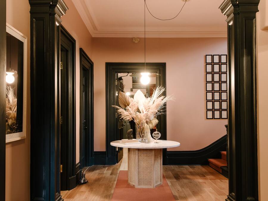 A hallway with a round table, a bench, and a staircase.