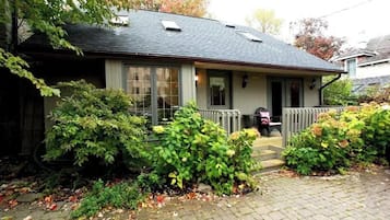 A two-story house with a front porch, a small garden, and a brick driveway.