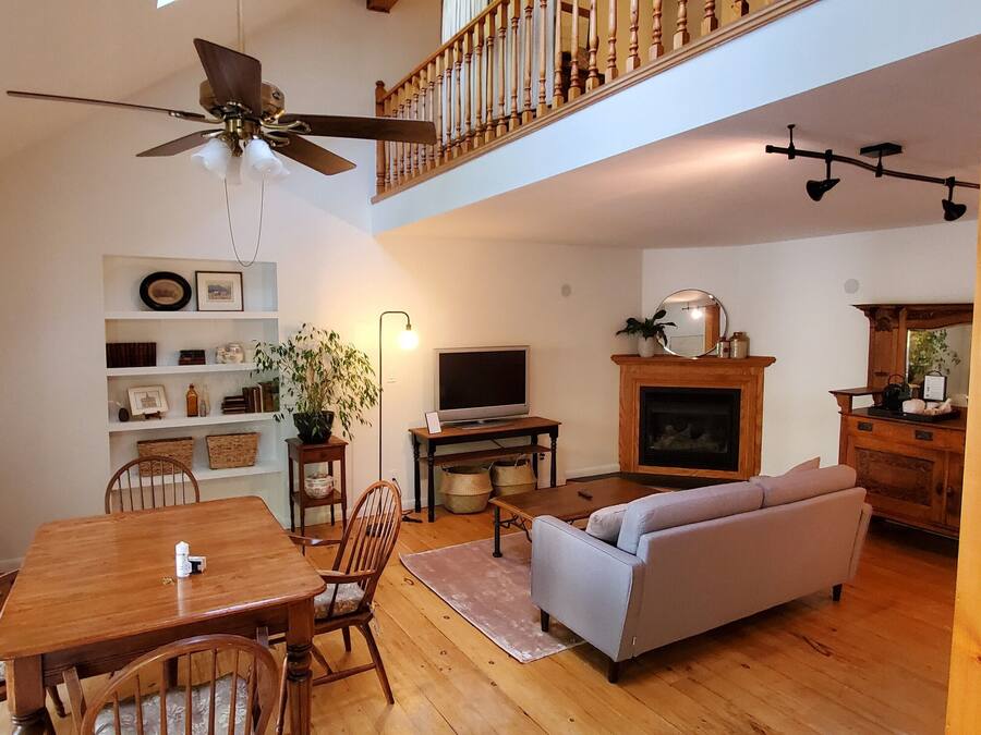 A spacious living room with a wooden dining table, a sofa, a television, and a fireplace.