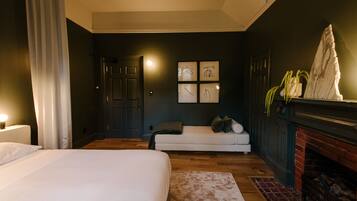 A bedroom with a bed, a sofa, a fireplace, and wall art.