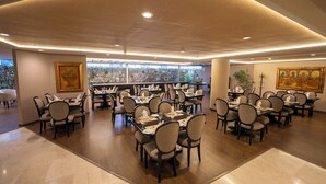 A spacious dining area with multiple tables and chairs, large windows, and framed artwork on the walls. - Jose Antonio Executive (Lima)