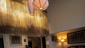 A hotel lobby with a reception desk, a seating area, and a large artwork on the wall. - Jose Antonio Executive (Lima)