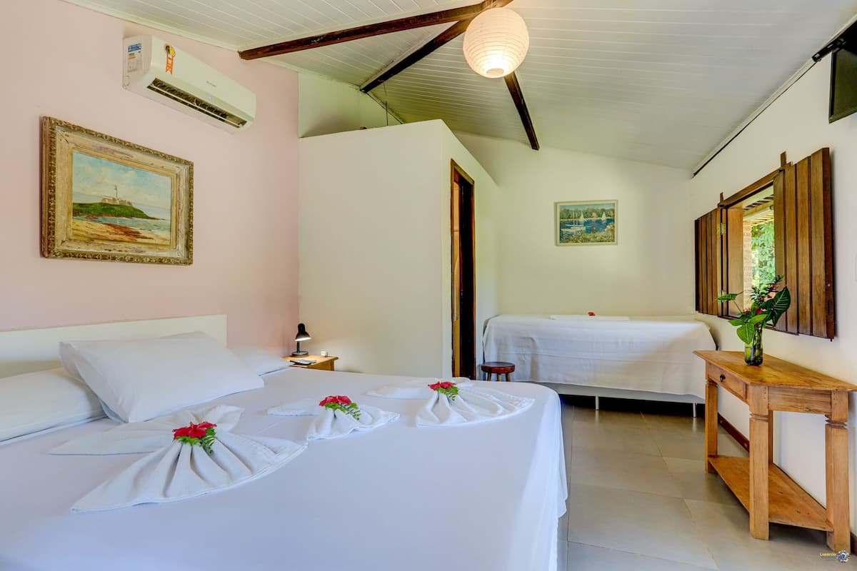 A hotel room with a bed, bedside table, and a small table with a plant.