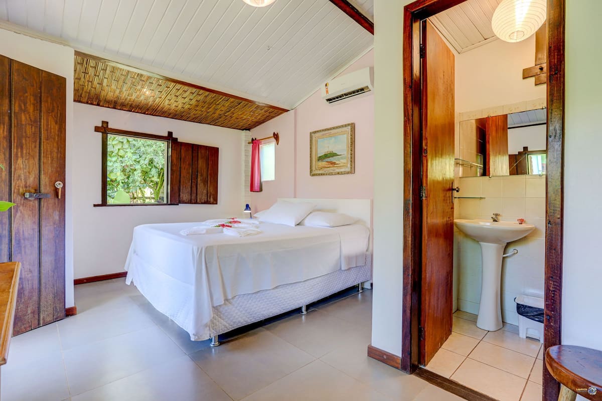 A bedroom with a bed, a window, a sink, and a mirror.
