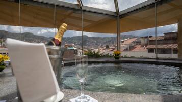 Ein Zimmer mit Blick auf eine Stadtlandschaft, ein Glas Champagner und eine Flasche in einem Glasbehälter.