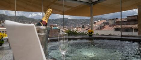 A room with a view of a cityscape, a glass of champagne, and a bottle in a glass container.