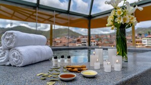 A spa area with a view of a cityscape, including a pool with candles and bath salts. - Jose Antonio Cusco Hotel (Cusco)