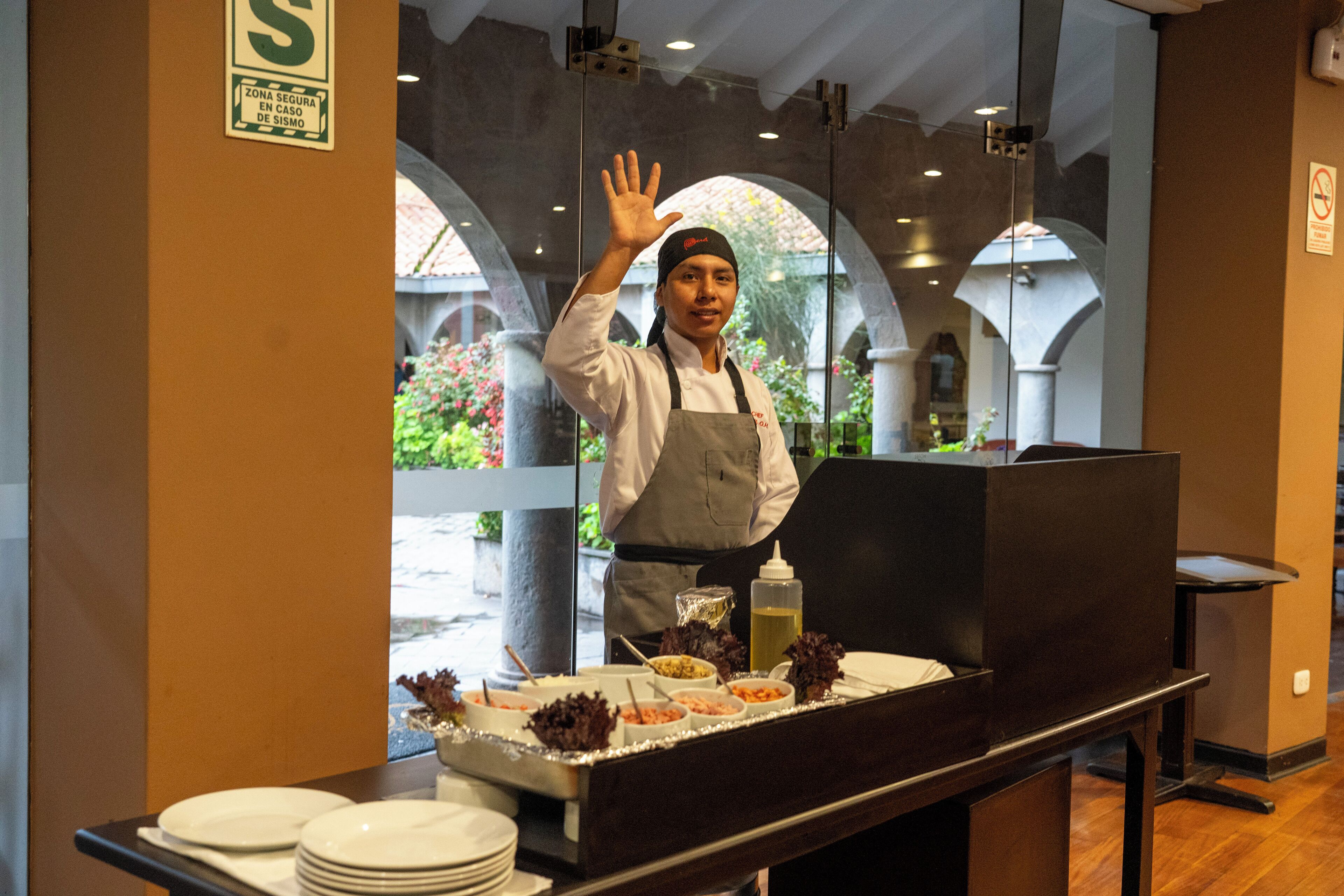 A buffet setup with various food items and a waiter in uniform.