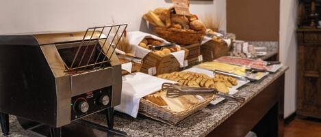 A buffet setup with a self-service grill, various baked goods, and a selection of pastries.