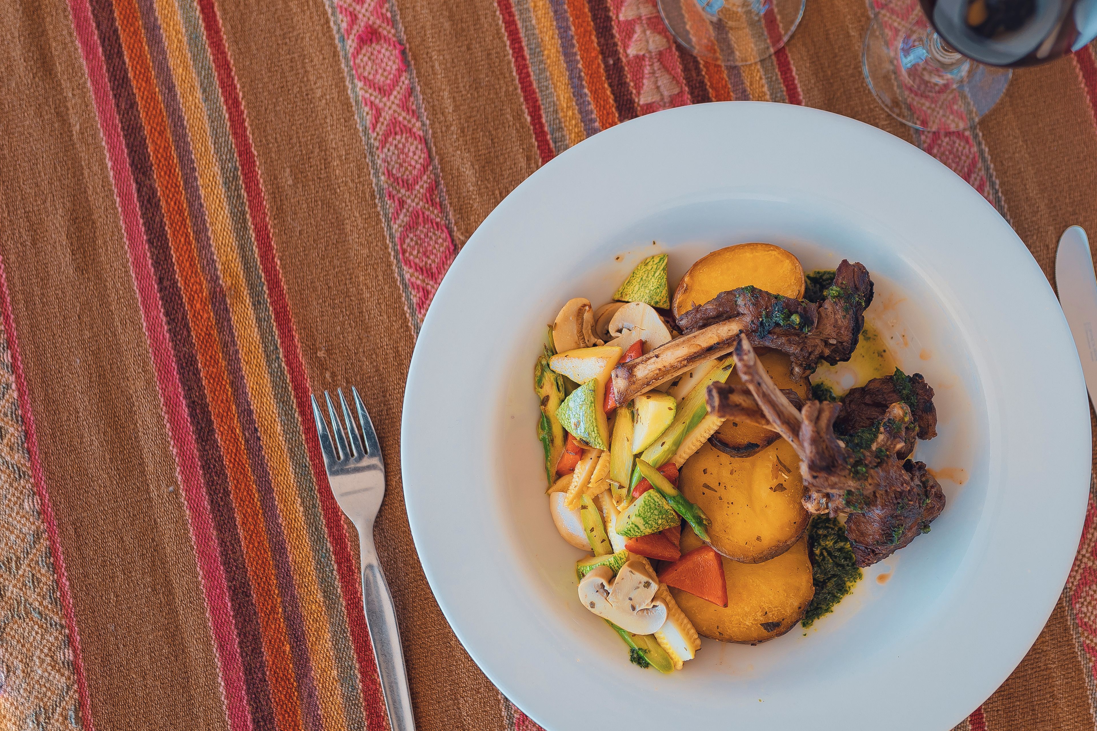 Un plato de comida con verduras y carne sobre un mantel.