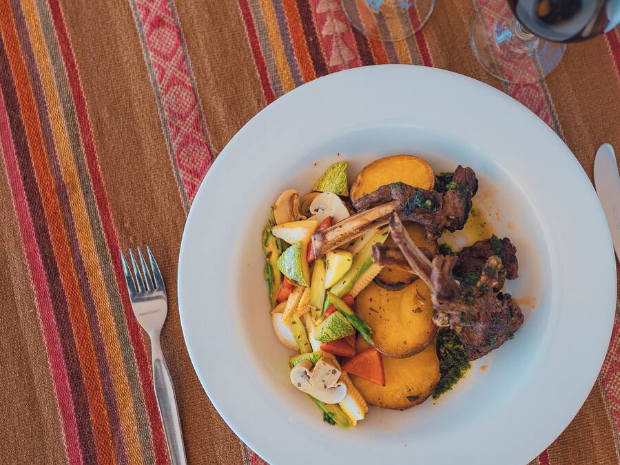 A plate of food with vegetables and meat on a tablecloth.