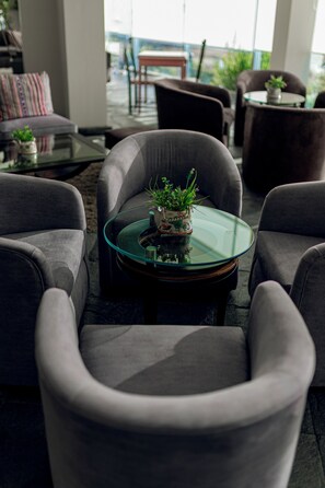 A modern living room with grey sofas, a glass coffee table with a plant, and a view of the outdoors.