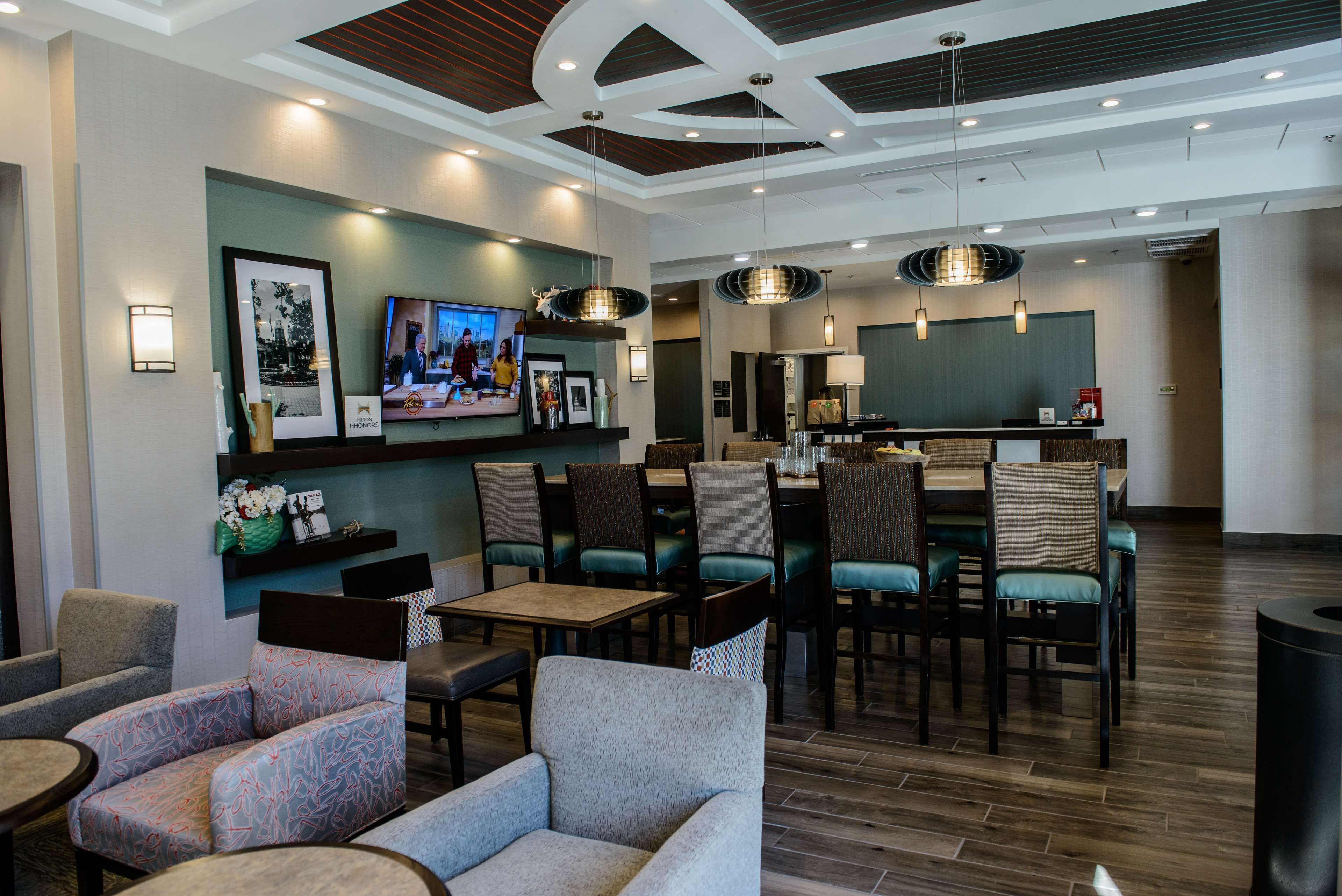 A hotel lobby with seating areas, a bar, and a television displaying a show.