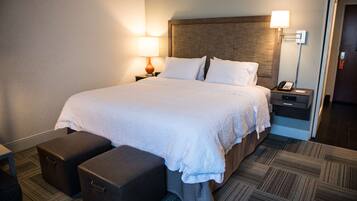 Habitación de hotel con una cama grande, dos mesitas de noche, una lámpara, un teléfono y un pequeño rincón de descanso.