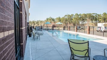 Una piscina al aire libre, sombrillas, sillones reclinables de piscina