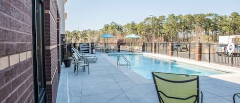 Una piscina al aire libre, sombrillas, sillones reclinables de piscina