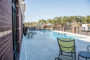 Una piscina al aire libre, sombrillas, sillones reclinables de piscina