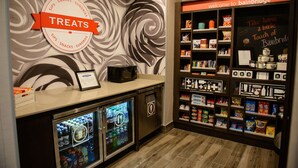 Un bar de aperitivos con un cartel que dice 'Treats', un microondas y un refrigerador lleno de bebidas.