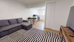 A modern living room with a grey sofa, a striped rug, and a wooden side table. - The Atlantic, BW Signature Collection (Ocean City)
