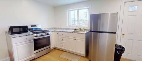 A kitchen with white cabinets, a stainless steel refrigerator, a microwave, and an oven.