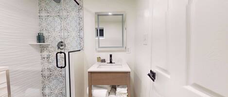 A bathroom with a shower, a sink, and a mirror.