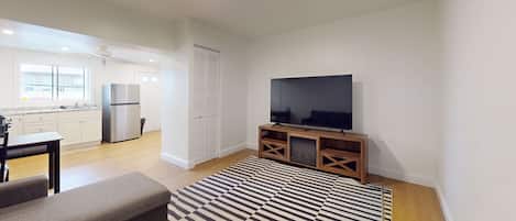 A modern living room with a flat-screen TV, a sofa, and a patterned rug.