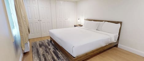 Un dormitorio con cama, mesita de noche, lámpara y armario.