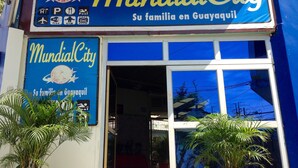 The exterior of a hotel named 'MundialCity' with a sign indicating amenities like a pool, gym, and Wi-Fi. - MundialCity Hotel Guayaquil (Guayaquil)