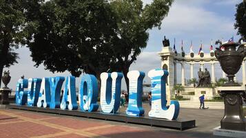A large outdoor sign with the word "HAYQUIL" in blue letters, surrounded by trees and a statue in the background.