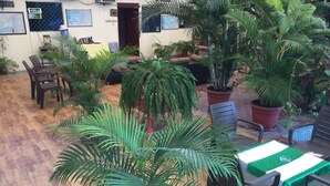A room with wooden flooring, multiple chairs, a table with a green tablecloth, and various potted plants. - MundialCity Hotel Guayaquil (Guayaquil)