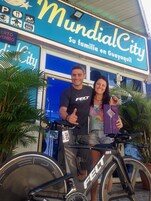 Una pareja de pie frente a una tienda llamada "MundialCity" con una bicicleta.