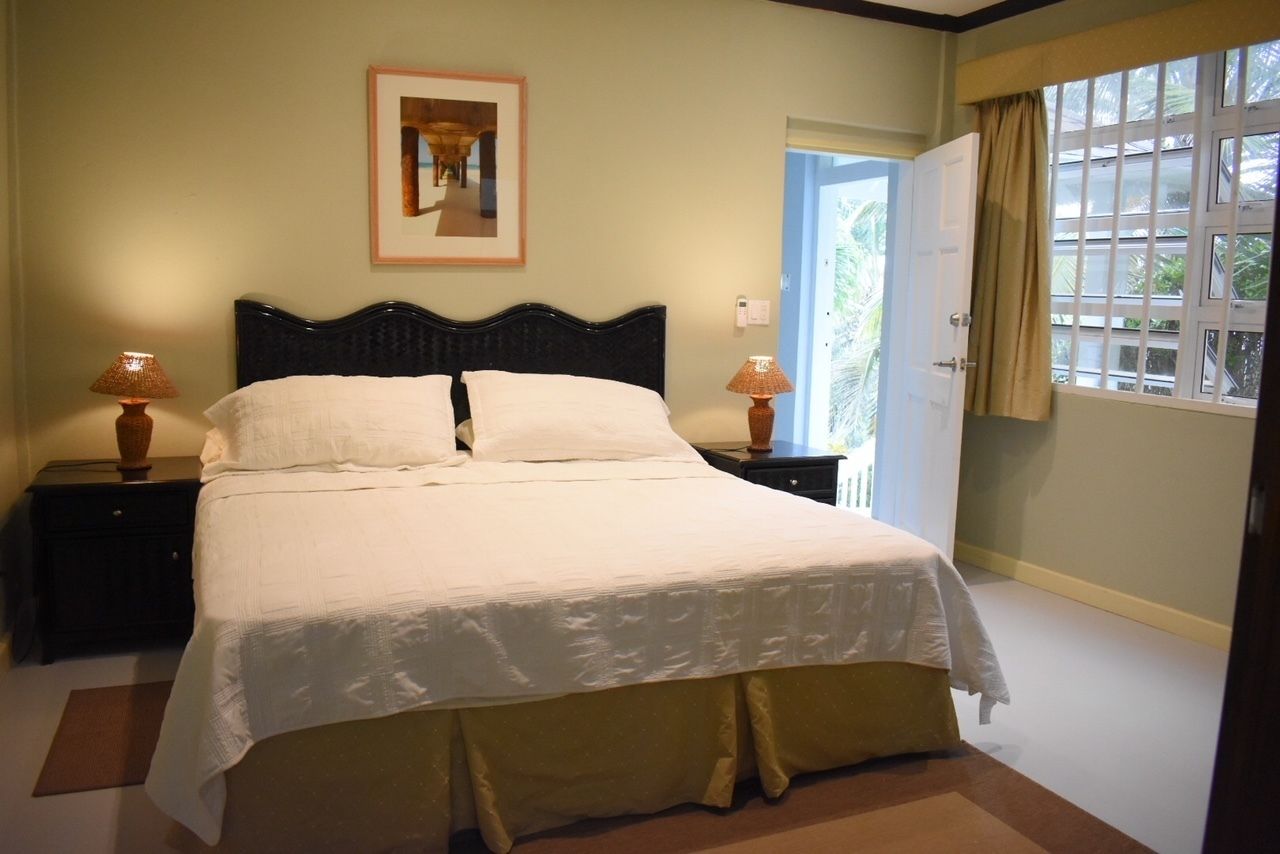 A neatly made bed with white linens, two bedside lamps, and a framed picture on the wall.
