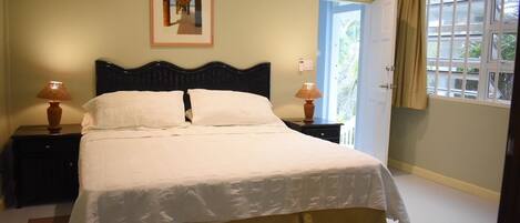 A neatly made bed with white linens, two bedside lamps, and a framed picture on the wall.