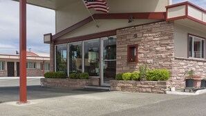 A building with a stone facade, large windows, and an American flag. - Flagstone Motel (Port Angeles)