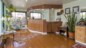 A reception area with a wooden desk, a bulletin board, and a potted plant. - Flagstone Motel (Port Angeles)